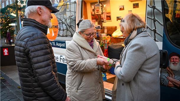 Ingrid Gottschalk (Mitte) verteilt nach Kontrolle des Impfnachweises die Armbänder an die Bremerhavener Christa und Jörg Fischoeder.