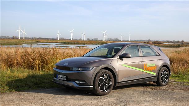 Hyundai Ioniq 5 steht vor Schilffeldern und einem Windpark im Hintergrund
