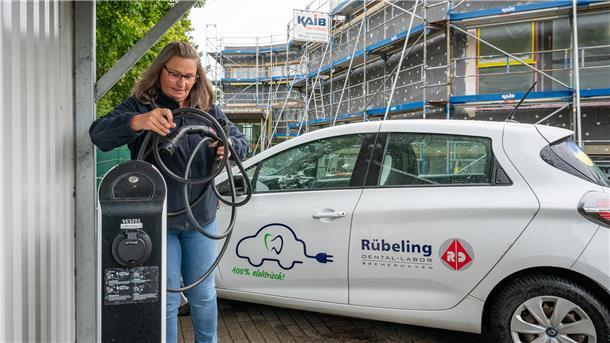 Investition in Klimaschutz: Das Dentallabor von Frank Rübeling hat einen E-Auto-Fuhrpark. Mitarbeiterin Rita Schalk steht vor einer von sechs Ladesäulen. Aktuell wird zudem das Haus neu gedämmt.