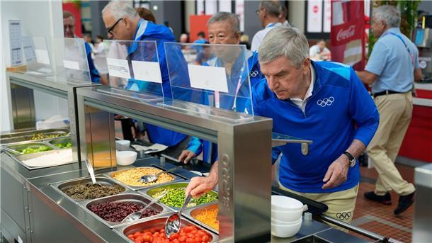 IOC-Präsident Thomas Back kostet vom Essen im Olympischen Dorf.