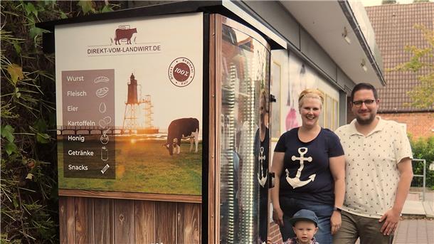Ein Mann und eine Frau stehen neben einem Automaten mit Lebensmitteln.