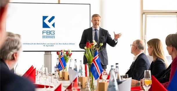 Ein Mann spricht stehend vor mehreren sitzenden Menschen. Auf einem großen BIldschirm hinter ihm ist das Wort "FBG" und das blau-weiße Logo des Unternehmens zu lesen. Island und Bremerhaven verbindet eine lange Partnerschaft in der Fischwirtschaft – Botschafter Auðunn Atlason würdigte beim Besuch des Fischereihafens die enge und verlässliche Zusammenarbeit. 