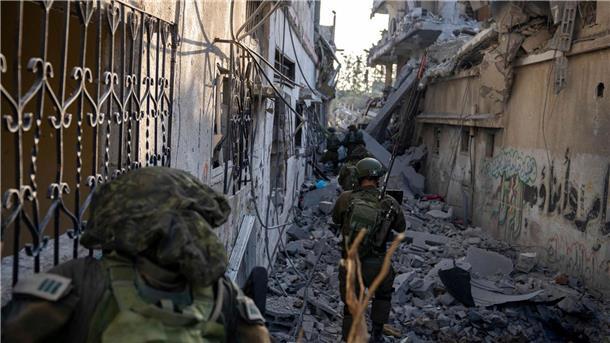 Israelische Soldaten gehen zwischen zerstörten Häusern: Israels Militär hat nach eigenen Angaben die Stadt Gaza umstellt.