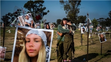 Israelische Soldatinnen stehen zwischen Fotos getöteter Israelis am Ort des Massakers beim Re’im-Musikfestival in der Negev-Wüste.