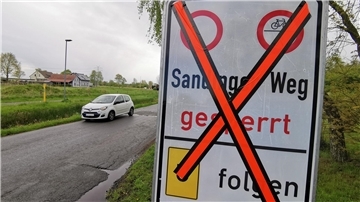 Straße mit Auto, daneben ein Hinweisschild