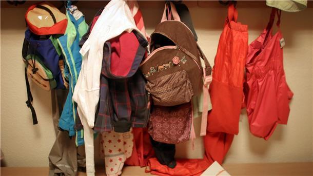 Viele Unternehmen unterstützen Familienplanung Jacken und Rucksäcke von Kindern in der Garderobe einer Betriebskita.