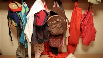 Jacken und Rucksäcke von Kindern in der Garderobe einer Betriebskita.