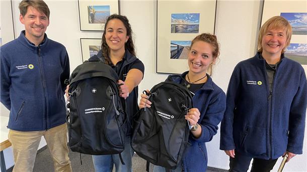 Jan Wagner von der Nationalparkverwaltung hatte für Elena Reiriz Martínez und Lucy Drenker (von links) je einen mit allerlei nützlichen Dingen gefüllten Rucksack als Abschiedsgeschenk dabei. Dr. Anika Seyfferth, eine der beiden Leiterin des Nationalparkhauses in Fedderwardersiel, freute sich mit den jungen Frauen.