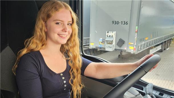 Eine junge Frau sitzt am Steuer eines Lkw.