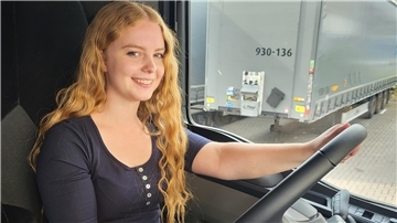 Eine junge Frau sitzt am Steuer eines Lkw.