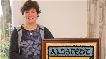 Jeanette Wolfermann, Ortsheimatpflegerin in Albstedt, mit einem Wappen der Ortschaft