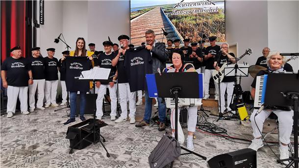 Jens Hillers und seine Tochter Selina haben dem Shantychor Butjenter Blinkfüer die T-Shirts während des jüngsten Auftritts in der Konzertmuschel in Tossens übergeben.
