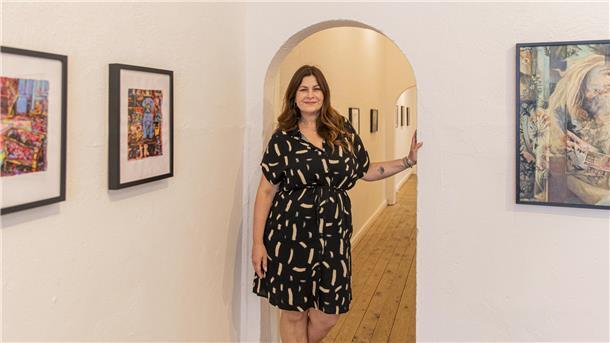 Künstlerin Jessica Russo Scherr steht in einer Galerie Bilder hängen an den Wänden