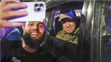 Jewgeni Prigoschin (r), Eigentümer des Militärunternehmens Wagner Group, sitzt in einem Militärfahrzeug und lässt ein Selfie mit einem Zivilisten auf einer Straße in Rostow am Don machen.