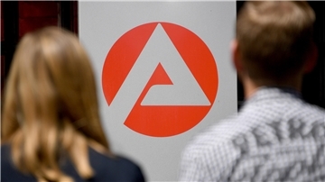 Zwei Personen stehen vor dem Logo der Agentur für Arbeit