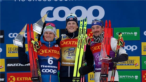 Moch Dritter auf der Alpe Cermis - Carl Gesamt-Achte Johannes Hoesflot Klaebo (M) aus Norwegen jubelt neben dem Zweitplatzierten Mika Vermeulen (l) aus Österreich und dem Drittplatzierten Hugo Lapalus aus Frankreich auf dem Podium der Tour de Ski.