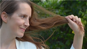 Eine Frau hält ihre langen Haare in die Kamera. 