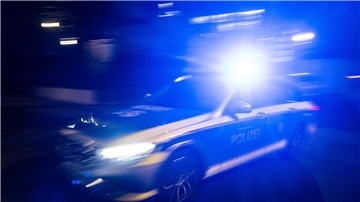 Ein Polizeifahrzeug fährt mit Blaulicht an einem Gebäude vorbei.