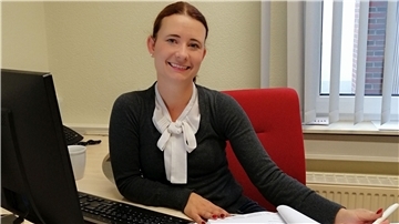 Frau mit Anzug sitzt an einem Schreibtisch.