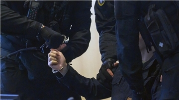Justitzbeamte nehmen dem Angeklagten im Gerichtssaal die Handschellen ab.