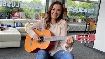 Eine Frau hält eine Gitarre in den Händen.