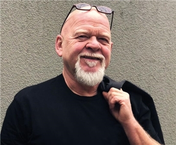 Ein Mann in schwarzer Kleidung hat einen grauen Bart und lächelt. Eine Brille ist auf seiner Glatze. Er lächelt. Kabarettist Bernd Gieseking nimmt das Publikum mit auf seine witzige Reise durchs Älterwerden – und zur Zugspitze.