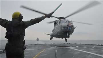 Ein Mann und ein Hubschrauber an Deck eines Schiffes