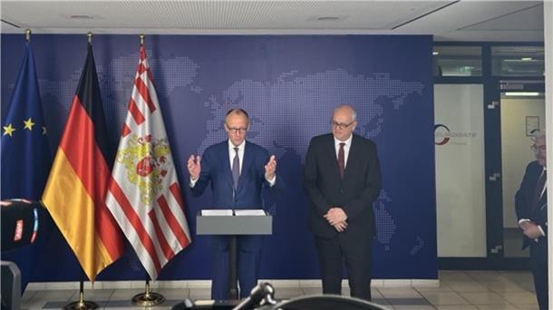 Friedrich Merz und Andreas Bovenschulte bei einem Statement im Eurogate-Gatehouse in Bremerhaven vor EU-, Deutschland- und Bremen-Flagge