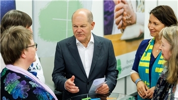 Kanzler Olaf Scholz unterhält sich bei einem Rundgang auf dem Messegelände.