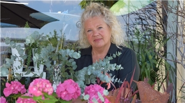 Karin Meißner-Brown steht hinter bunten Blumen. 