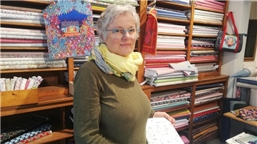 Eine Frau mit Brille vor einem Regal mit Stoffballen. Katrike Schloßhauer muss ihren Laden in der Hafenstraße schließen.