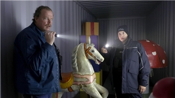 Zwei Zollbeamte stehen mit Taschenlampen in einem Container.