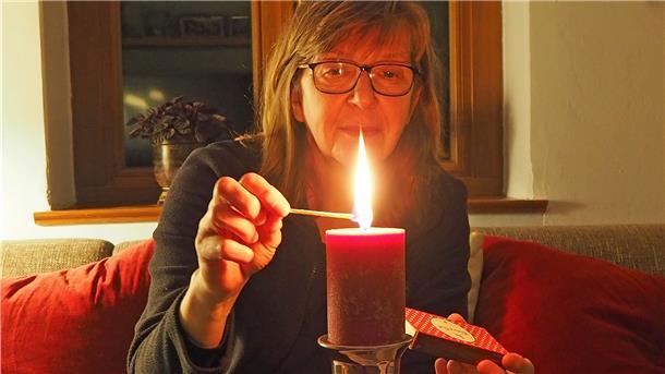 Frau zündet Kerze an.