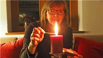 Frau zündet Kerze an.