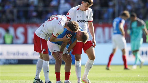 Kiels Lewis Holtby wird nach dem Abstieg von den Freiburgern Patrick Osterhage (l) und Maximilian Eggestein getröstet.