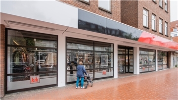 eine KiK-Filiale vor der Eröffnung, eine Frau mit Rollator wirft bereits einen Blick ins Schaufenster