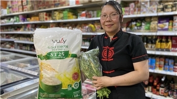 Eine Frau steht mit einem Sack Reis zwischen Regalen.