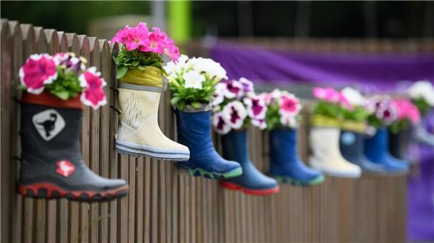 Kitas im Krisenmodus: Konferenz sucht Lösungen Kinder-Gummistiefel mit Blumen hängen an einem Zaun einer Kindertagesstätte.