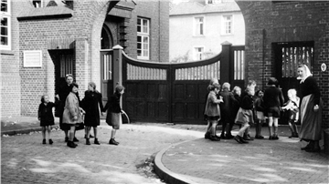 Kinder stehen vor der Einfahrt zu den Rotenburger Anstalten an einem geschlossenen Tor.