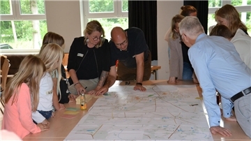 Kinder und Erwachsene beugen sich über einen Stadtplan von Zeven.