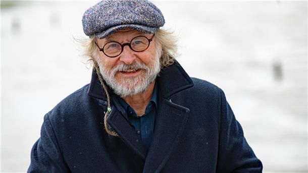 Mann mit Mütze, Brille und Bart. Krimi-Autor Klaus Peter Wolf liest in Tossens. 