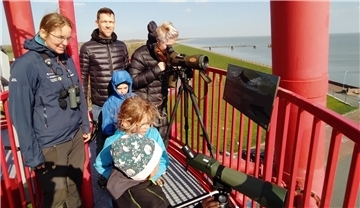 Erwachsene und Kinder stehen auf einem Leuchtturm und halten Ausschau