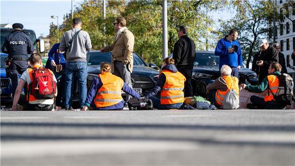 Klimaaktivisten haben sich am Karlsplatz in der Münchner Innenstadt auf die Fahrbahn geklebt und blockieren die Straße.