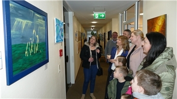 Künstlerin Christina Götte (mit Sektglas) zeigt ihren Gästen bei der Vernissage ihre Bilder. 