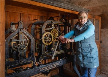 Küsterin Käte Heins am mechanischen Uhrwerk der Kirchwistedter Kirche: Mit der Kurbel bringt sie die Uhr zum Laufen.
