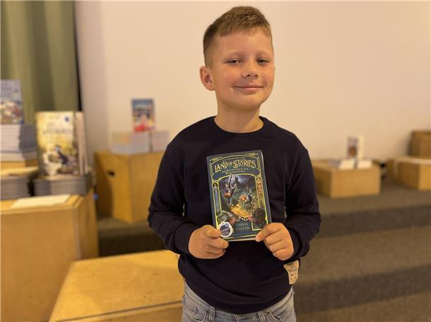 Ein Junge hält ein Buch. 