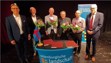 Sechs Männer hinter einem Rednerpult der Oldenburgischen Landschaft
