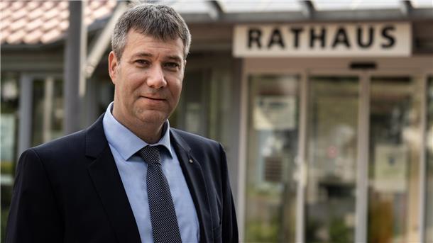Ein Mann blickt in die Kamera, im Hintergrund ist etwas unscharf das Wort "Rathaus" zu lesen. Lars Behrje aus Büttel denkt nach Informationen der NORDSEE-ZEITUNG über eine Kandidatur für das Amt des Loxstedter Bürgermeisters nach.