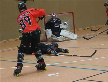 Ein Inlineskater-Hockeyfahrer schießt aufs Tor.