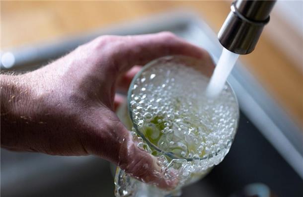 Tinkwasser läuft aus dem Wasserhahn in einer Küche in ein Glas